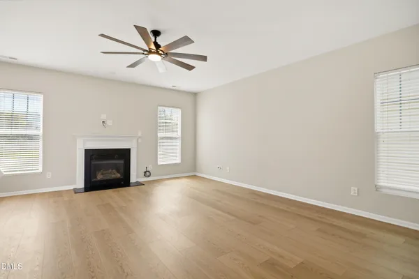 an empty room with windows and fireplace