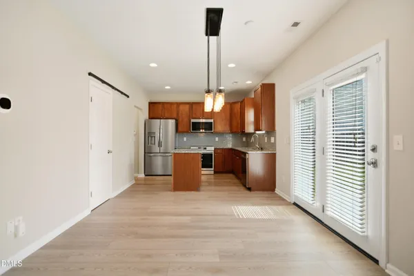 a kitchen with stainless steel appliances kitchen island granite countertop a refrigerator a sink a stove and a wooden floors
