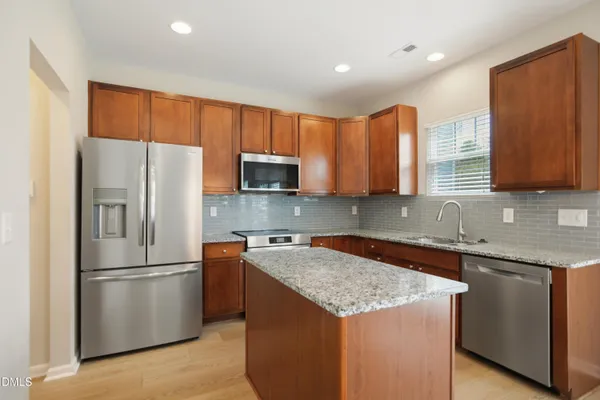 a kitchen with stainless steel appliances granite countertop a refrigerator a sink a stove a microwave and island
