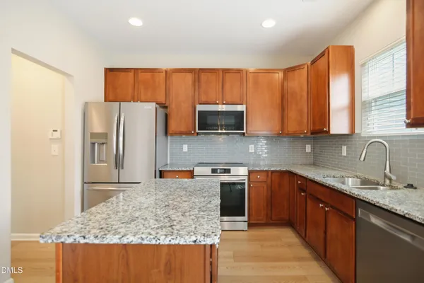a kitchen with stainless steel appliances granite countertop a refrigerator sink and microwave