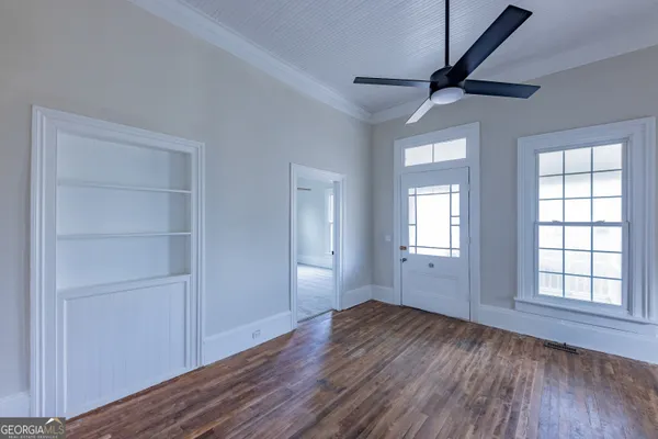 a view of empty room with wooden floor and fan