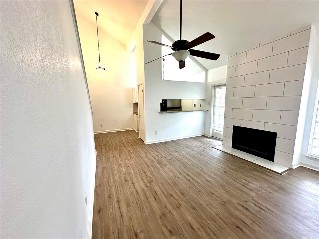 5981 Arapaho Road, Unit 1002 Dallas, TX 75248 - Photo 10 of 16 a view of a room with wooden floor a ceiling fan and staircase