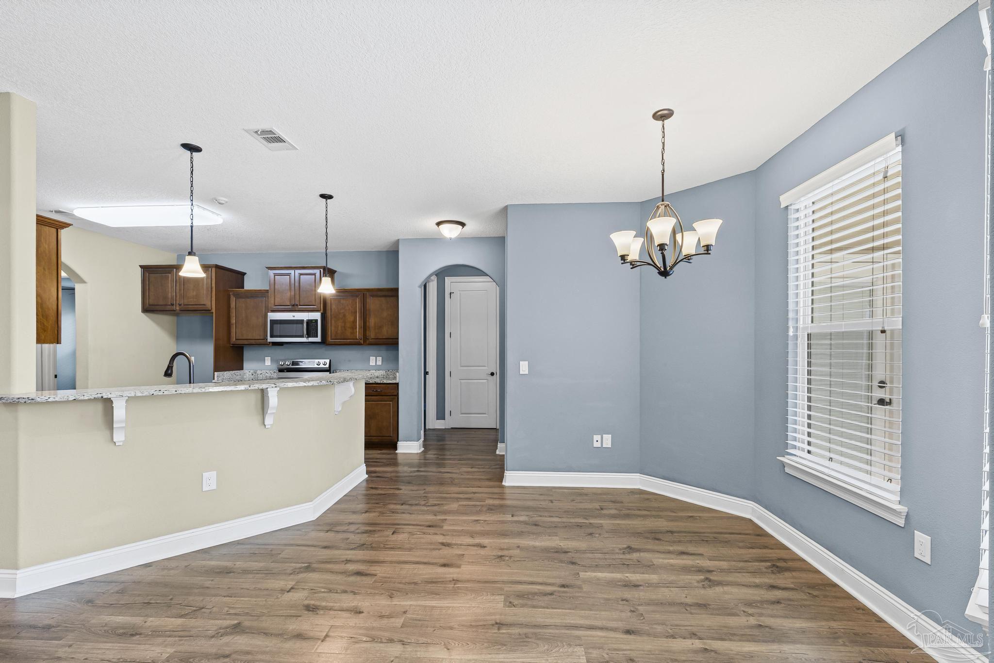 7933 Silver Maple Drive Milton, FL 32583 - Photo 24 of 70 a open kitchen with stainless steel appliances granite countertop a refrigerator a oven a stove and a wooden floors