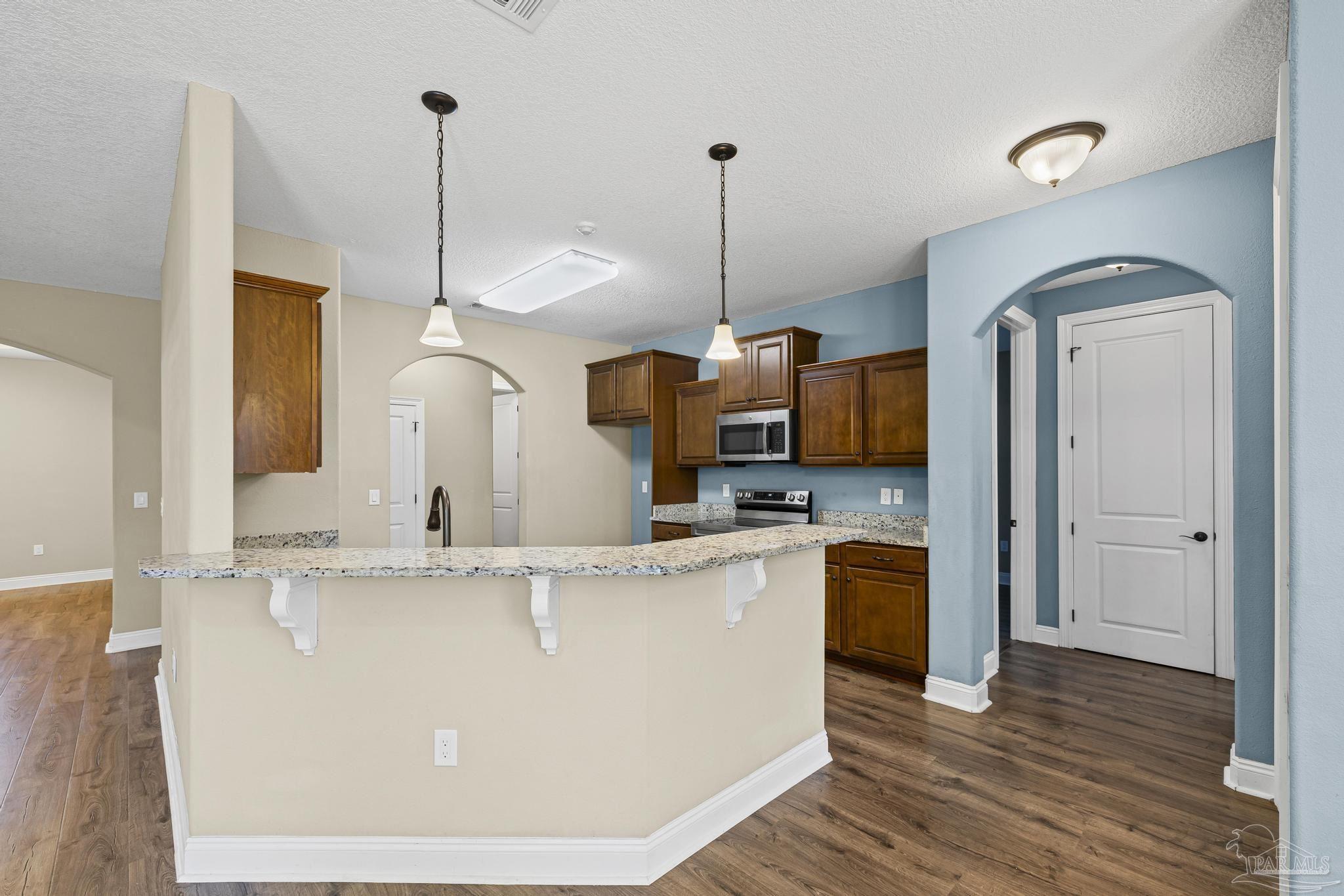 7933 Silver Maple Drive Milton, FL 32583 - Photo 27 of 70 a kitchen with stainless steel appliances granite countertop a sink a stove and a wooden floor