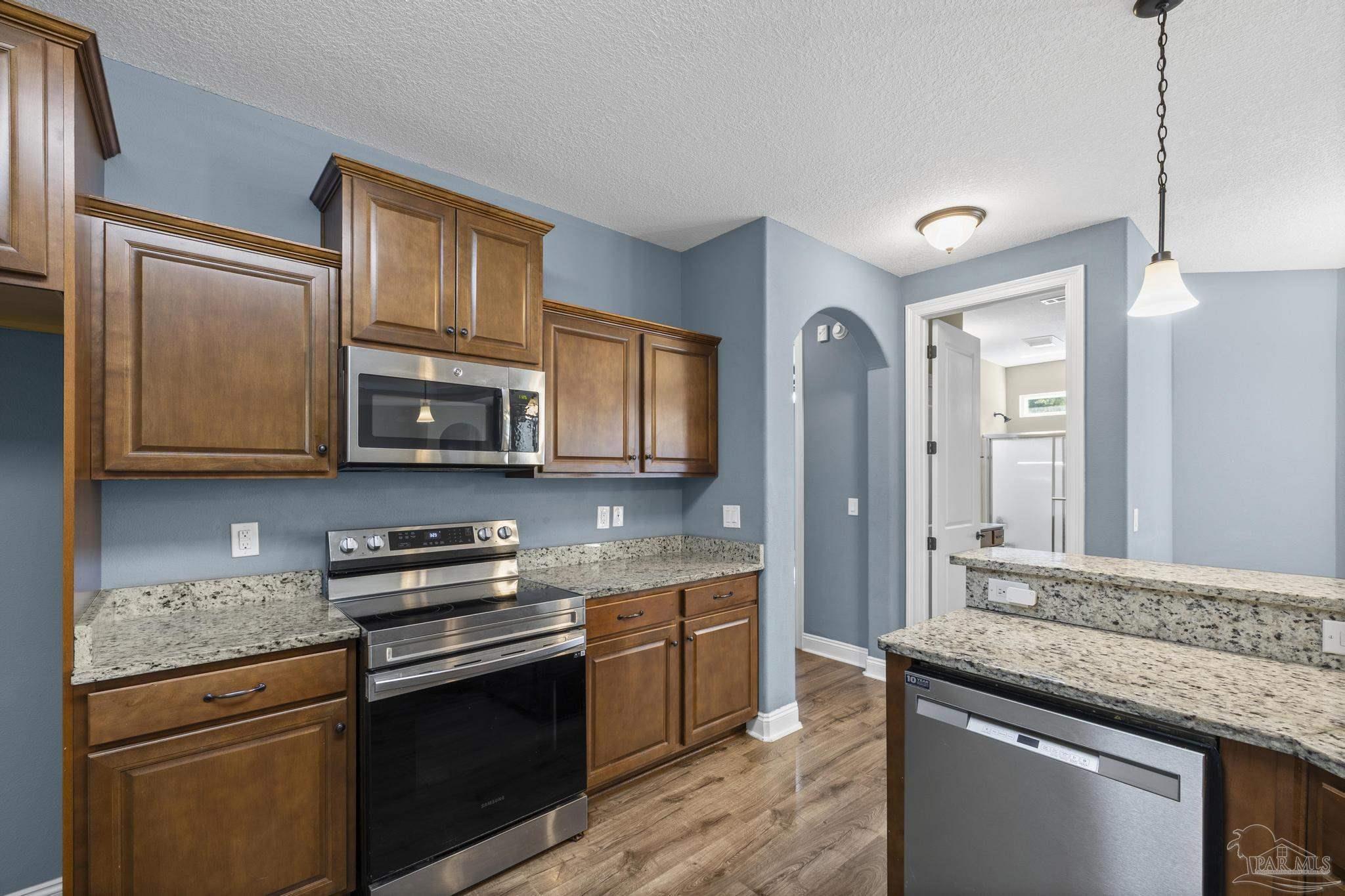 7933 Silver Maple Drive Milton, FL 32583 - Photo 29 of 70 a kitchen with stainless steel appliances granite countertop a stove a sink and a microwave