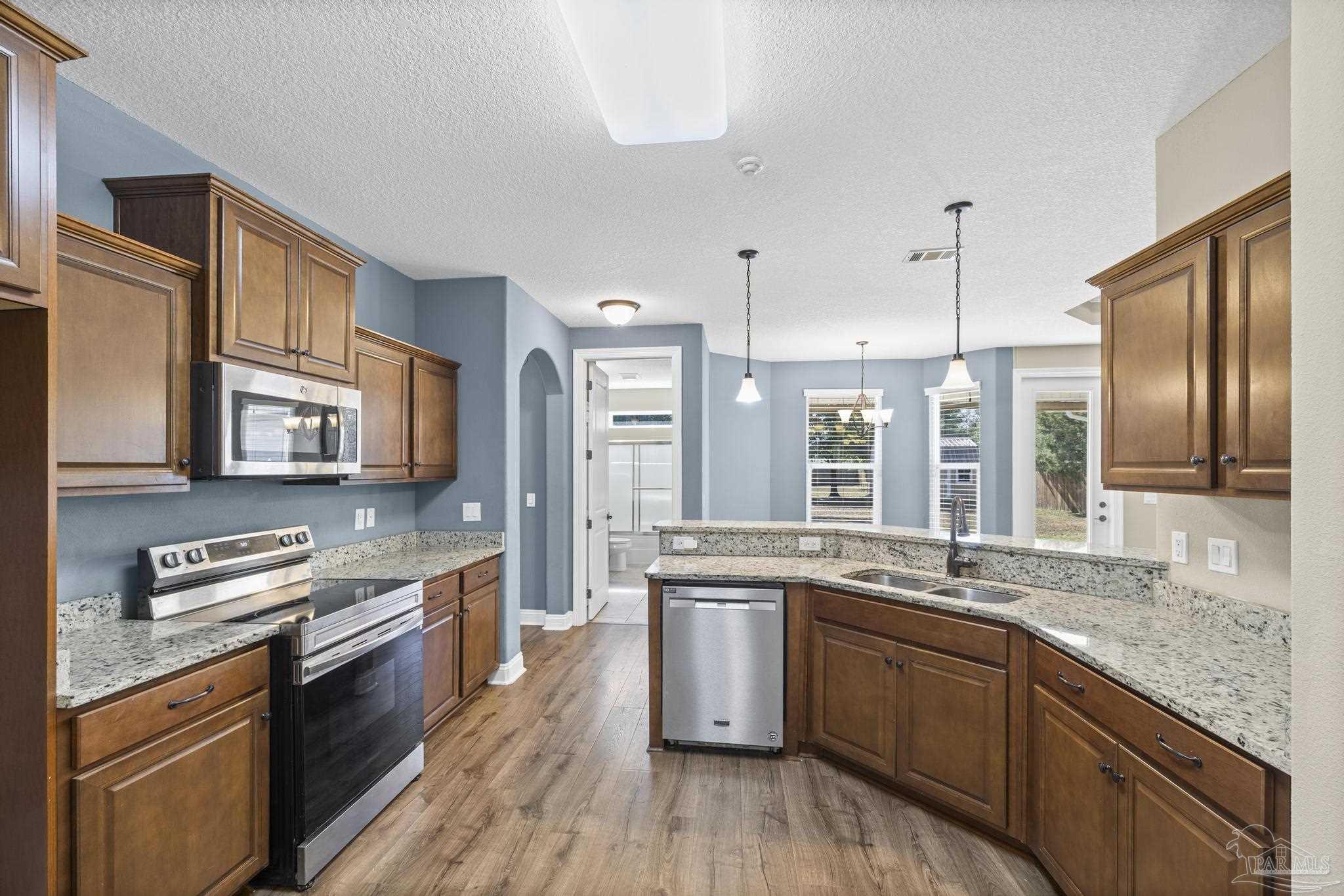 7933 Silver Maple Drive Milton, FL 32583 - Photo 30 of 70 a kitchen with stainless steel appliances granite countertop a sink stove and refrigerator