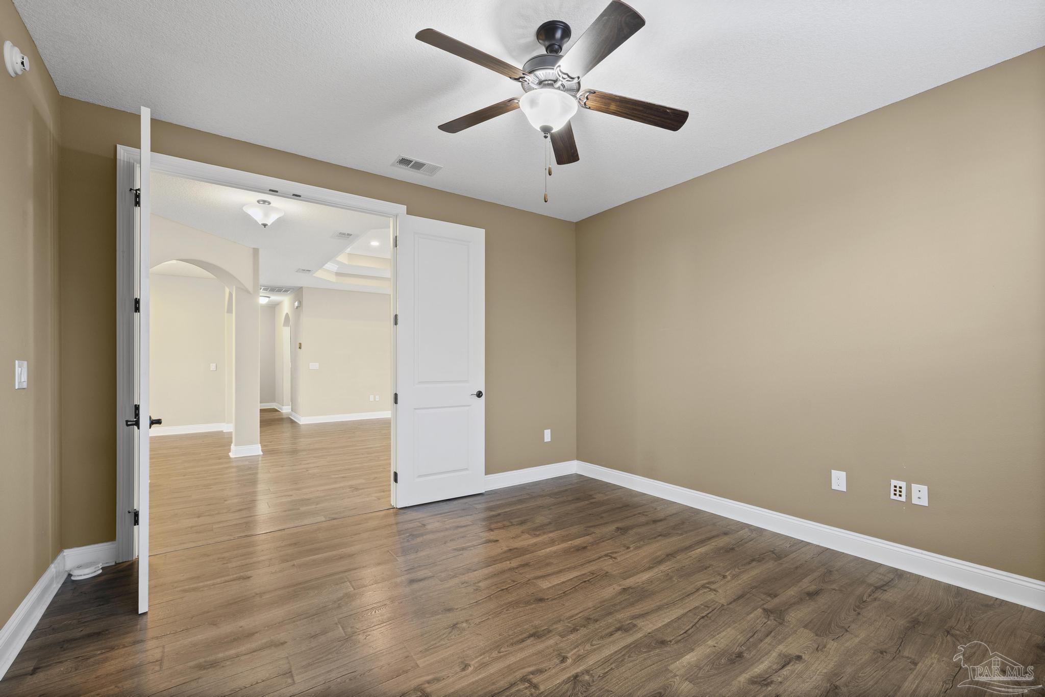 7933 Silver Maple Drive Milton, FL 32583 - Photo 35 of 70 an empty room with wooden floor and a ceiling fan