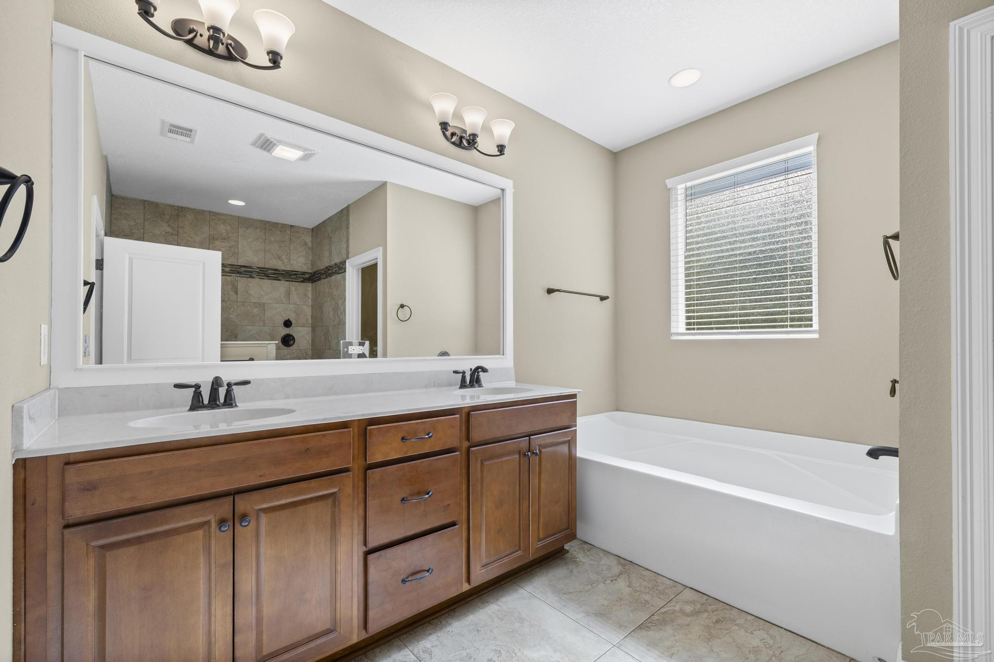 7933 Silver Maple Drive Milton, FL 32583 - Photo 38 of 70 a bathroom with a tub a sink double vanity and a mirror