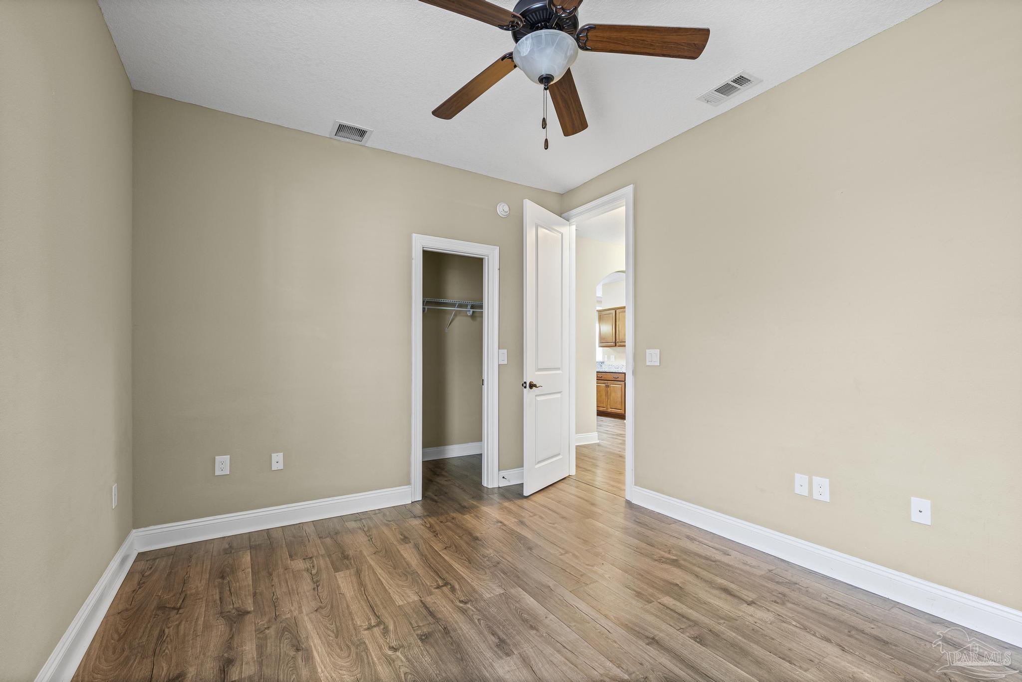 7933 Silver Maple Drive Milton, FL 32583 - Photo 42 of 70 an empty room with wooden floor and ceiling fan