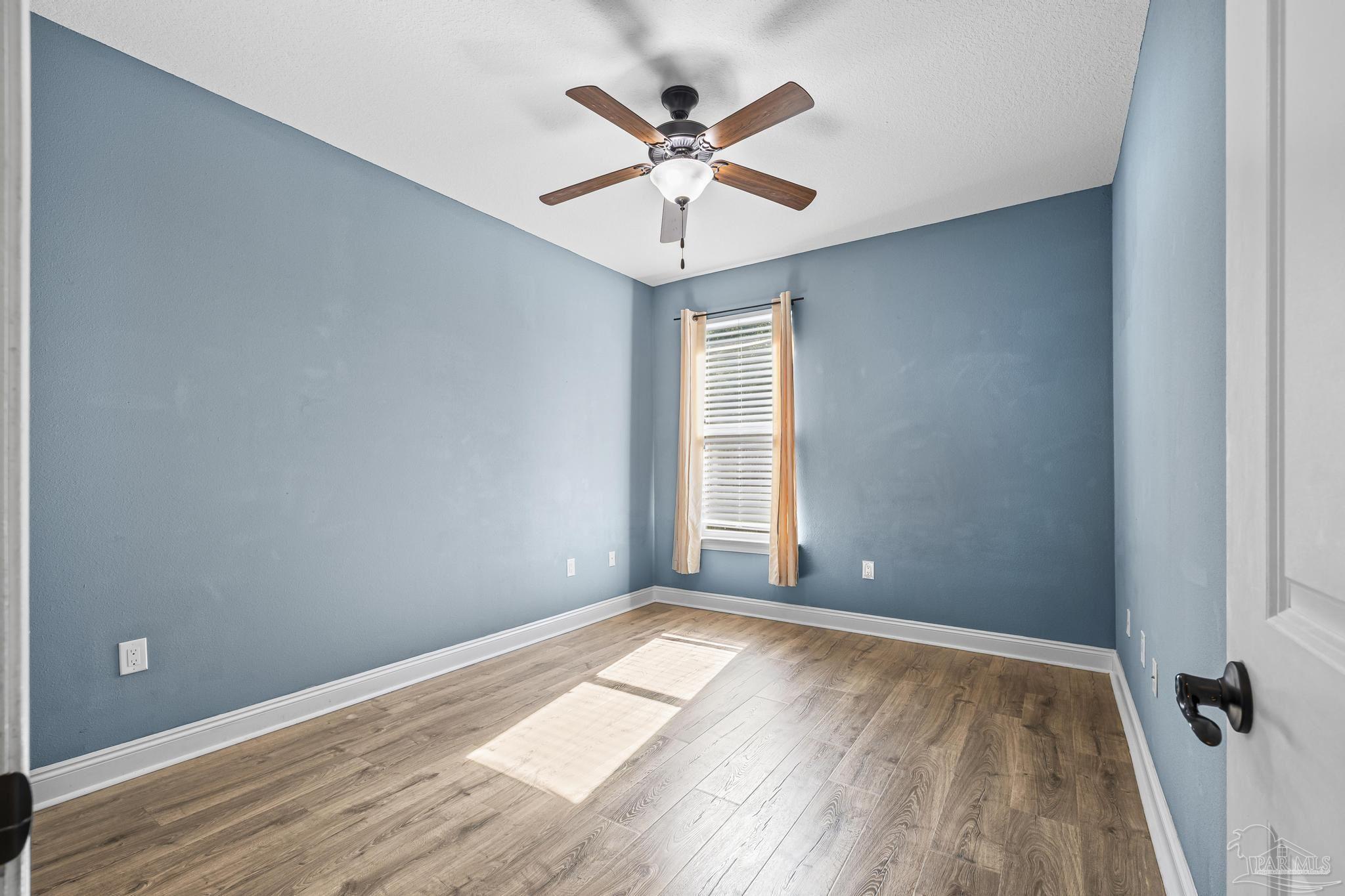 7933 Silver Maple Drive Milton, FL 32583 - Photo 47 of 70 an empty room with wooden floor fan and windows