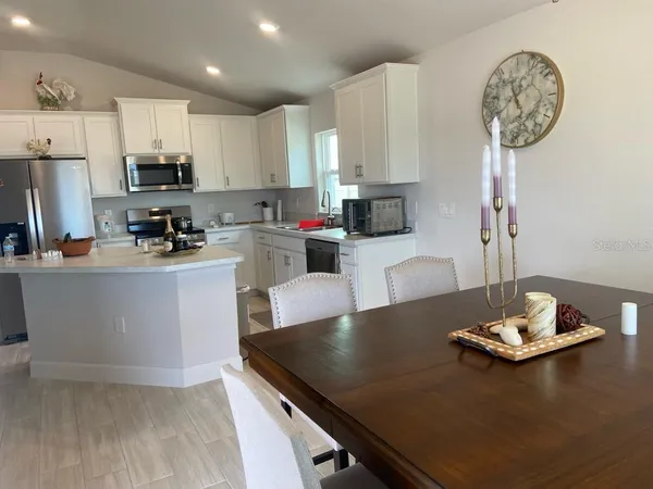 a kitchen with a refrigerator a stove a sink and a dining table with wooden floor