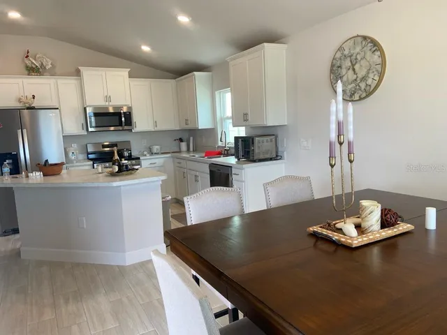 a kitchen with a refrigerator a stove a sink and a dining table with wooden floor