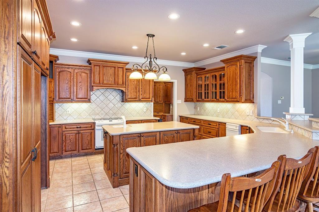 a kitchen with kitchen island granite countertop a stove a sink a refrigerator and chairs