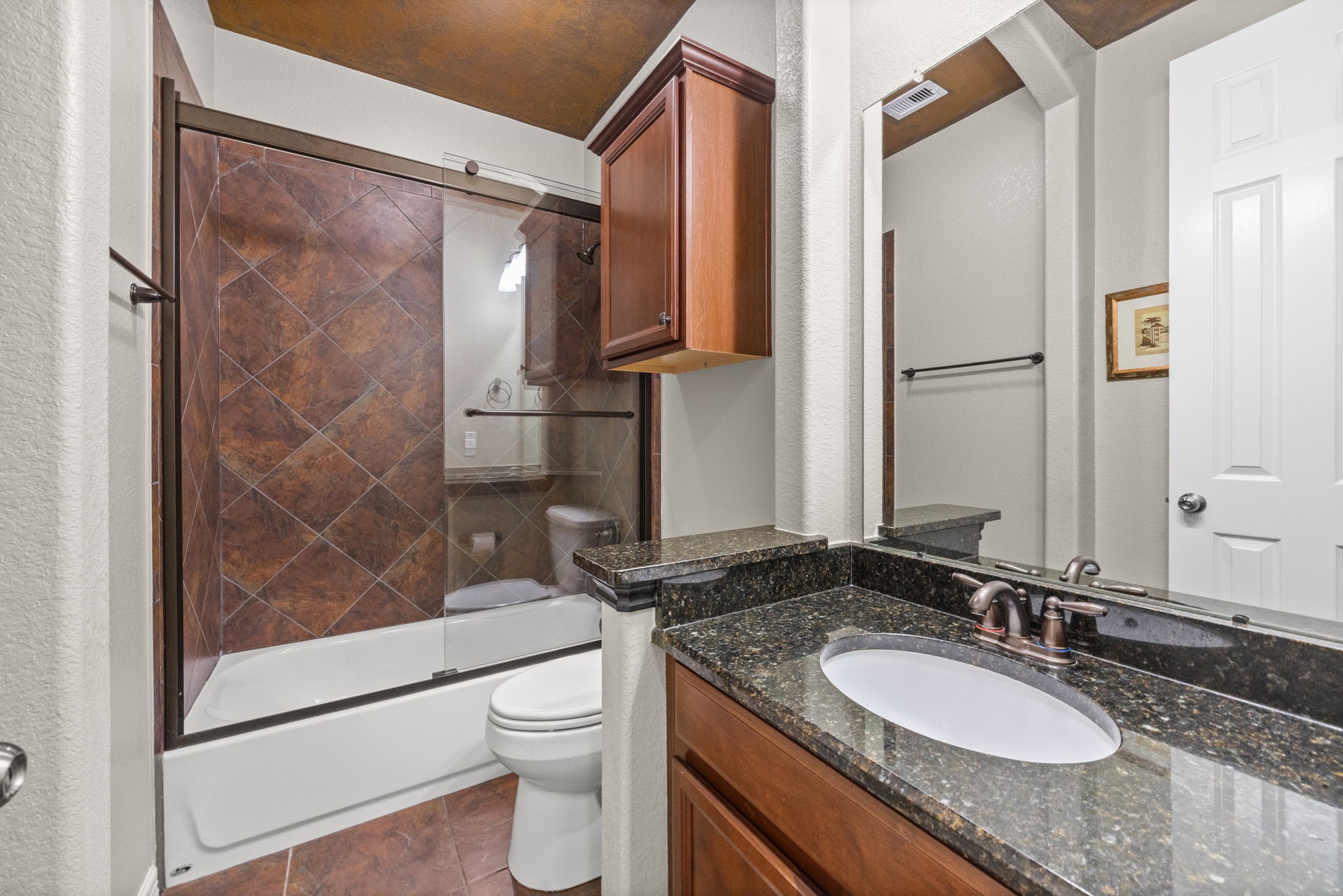 27642 Linden Ridge Lane Fulshear, TX 77441 - Photo 25 of 42 This Full Bath serves the secondary Bedrooms featured in the previous photos. It includes a granite countertop, oval undermount sink, oil-rubbed bronze faucet and coordinating light fixture, and a tub/shower combination with a sliding glass enclosure and decorative tile accents, offering both style and functionality.
