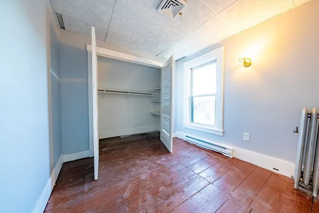 a view of an empty room with window and wooden floor