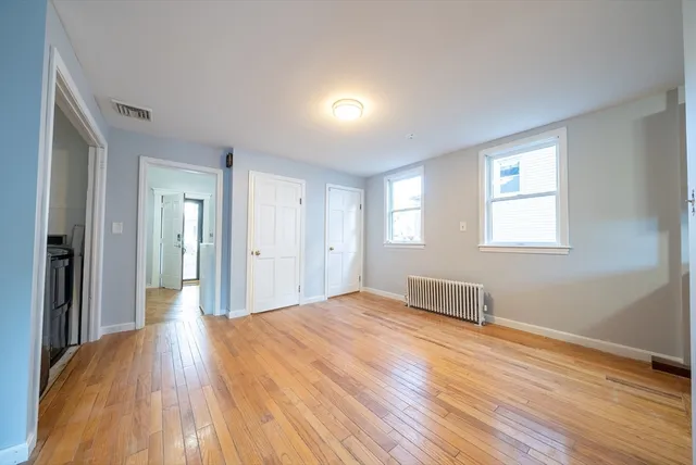 a view of a big room with wooden floor and windows