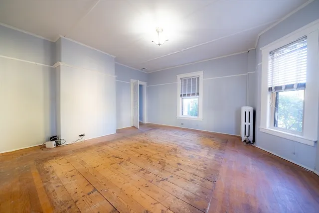 a view of empty room with window and wooden floor