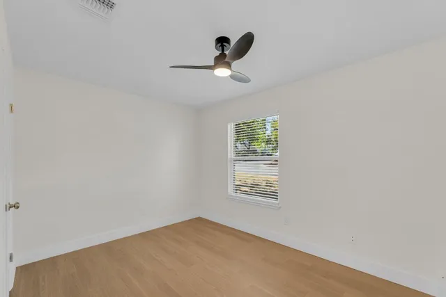 a view of a backyard with wooden fence and a large tree