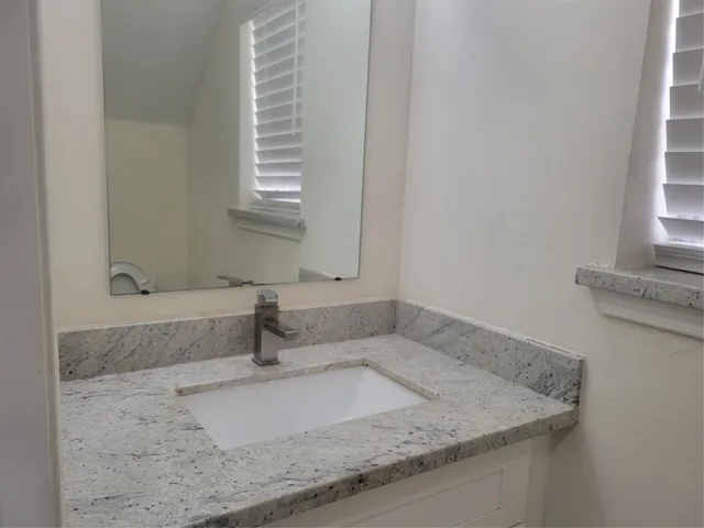a bathroom with a granite countertop sink and window