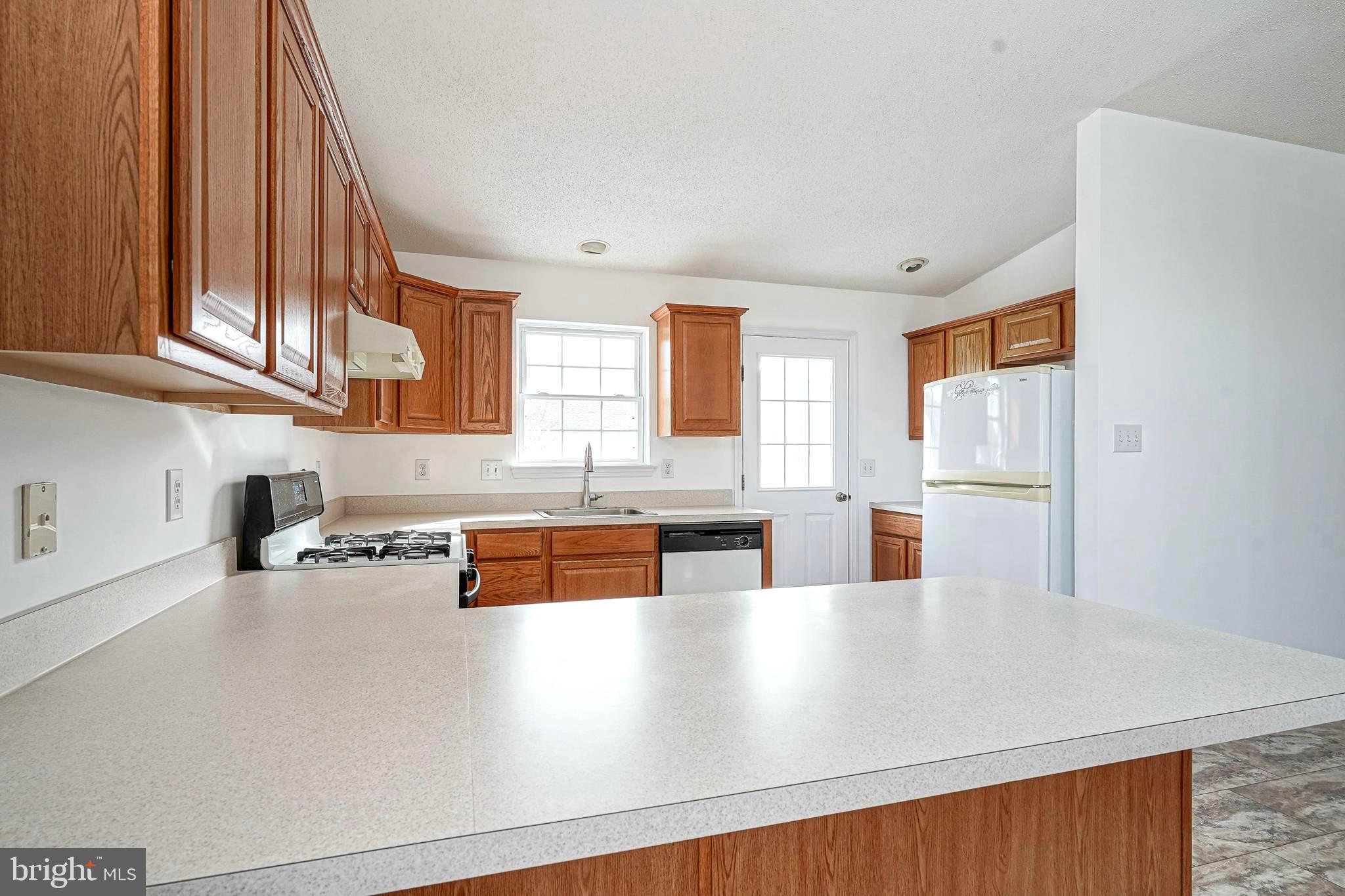 176 Trellis Lane Sewell, NJ 08080 - Photo 12 of 27 a kitchen with stainless steel appliances granite countertop a refrigerator a sink dishwasher a stove with wooden cabinets and floor