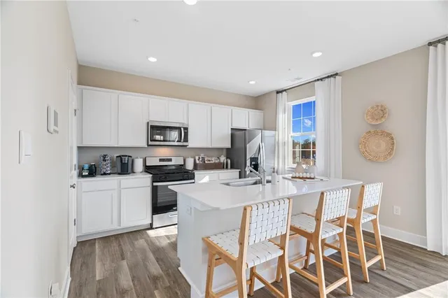 a kitchen with granite countertop stainless steel appliances a stove a sink a refrigerator cabinets and a dining table