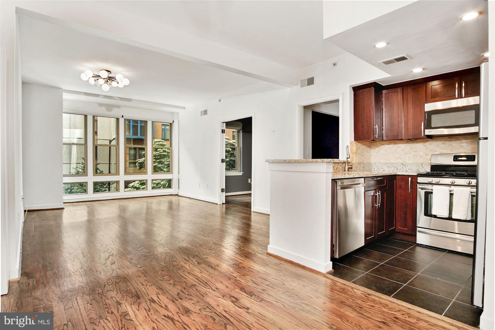 1445 N Street Northwest, Unit 202 Washington, DC 20005 - Photo 5 of 23 a view of a kitchen with stainless steel appliances granite countertop a stove top oven a sink dishwasher and white cabinets with wooden floor