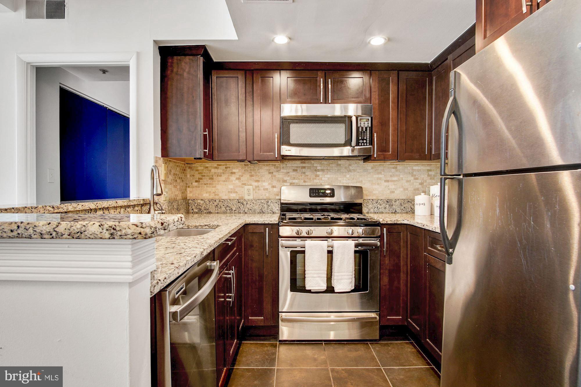 1445 N Street Northwest, Unit 202 Washington, DC 20005 - Photo 8 of 23 a kitchen with stainless steel appliances granite countertop a refrigerator stove microwave and sink