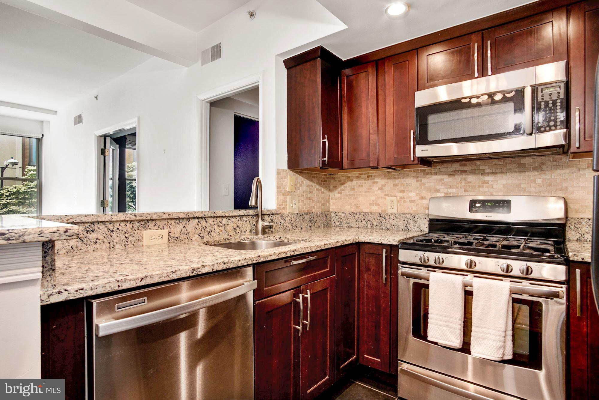 1445 N Street Northwest, Unit 202 Washington, DC 20005 - Photo 9 of 23 a kitchen with stainless steel appliances granite countertop a stove sink and cabinets