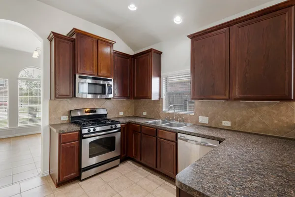 a kitchen with stainless steel appliances granite countertop a stove a sink and a microwave
