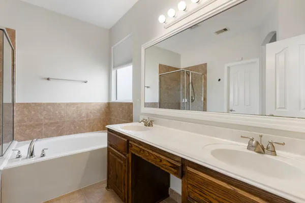 a bathroom with a sink double vanity granite tub tub and a mirror