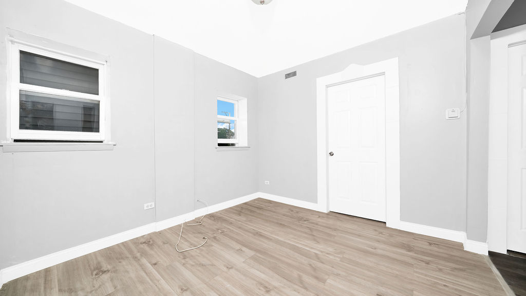 1831 West 21st Place, Unit 1R Chicago, IL 60608 - Photo 3 of 10 an empty room with wooden floor and windows