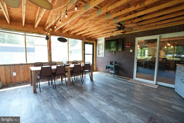 a dining room with furniture a floor to ceiling window and wooden floor