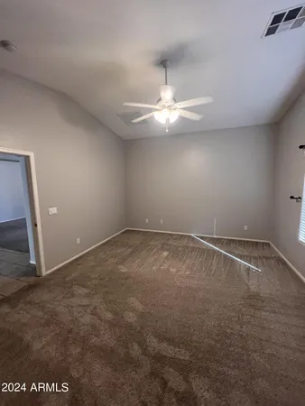 an empty room with chandelier fan and windows