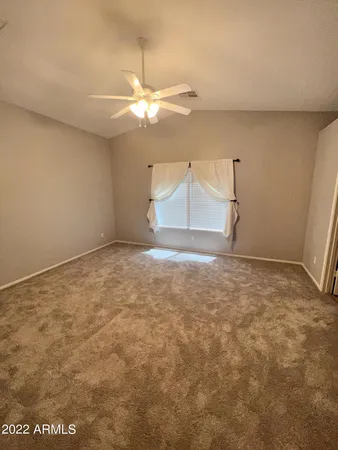 an empty room with a ceiling fan and carpet