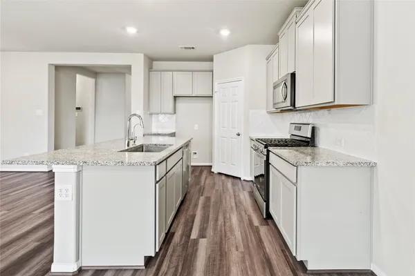 a kitchen with granite countertop a sink stove and refrigerator