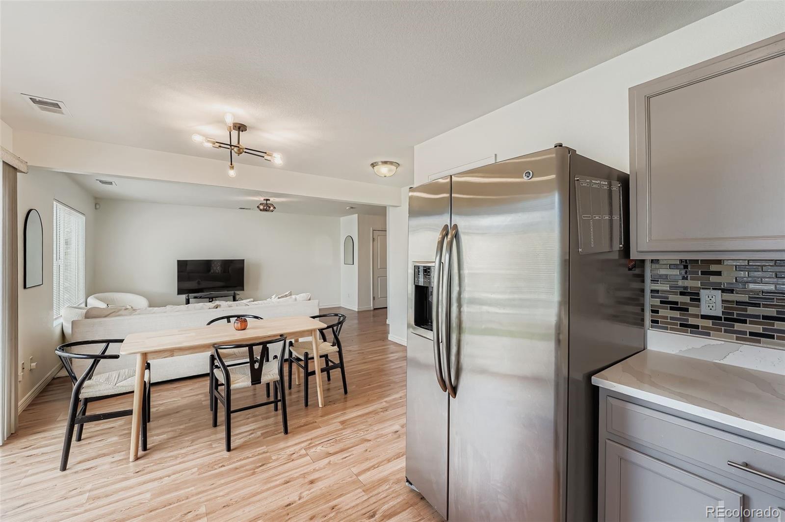 4250 Perth Circle Denver, CO 80249 - Photo 12 of 31 a kitchen with stainless steel appliances a refrigerator a stove a microwave a dining table and chairs with wooden floor