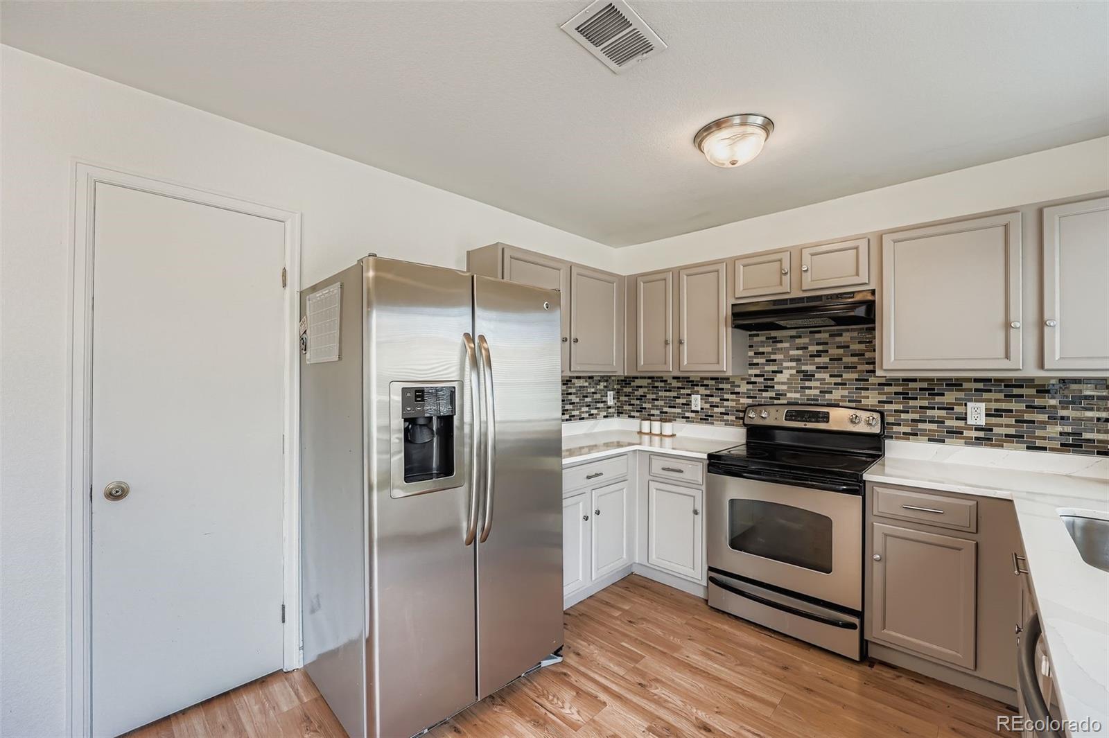 4250 Perth Circle Denver, CO 80249 - Photo 9 of 31 a kitchen with stainless steel appliances a stove a refrigerator and white cabinets