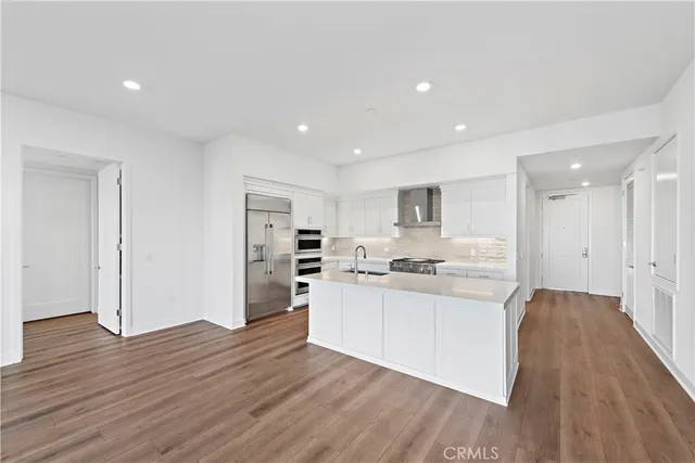 a large kitchen with stainless steel appliances granite countertop a stove and a wooden floors