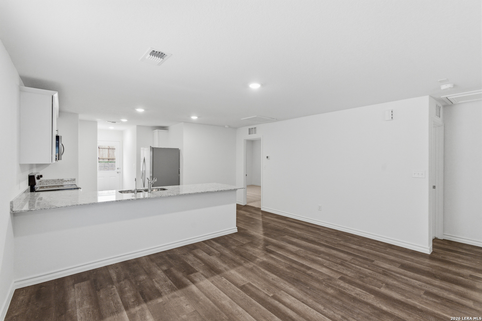 10107 Monte Carmel Place Adkins, TX 78101 - Photo 11 of 25 a large white kitchen with wooden floor and a sink