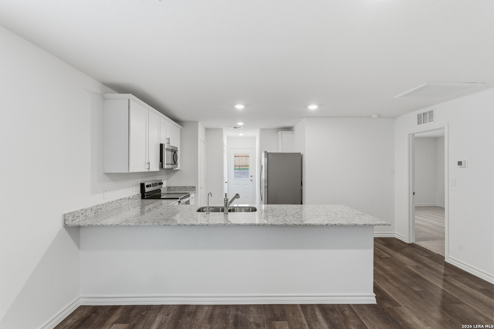 10107 Monte Carmel Place Adkins, TX 78101 - Photo 4 of 25 a large white kitchen with kitchen island granite countertop a sink and a refrigerator