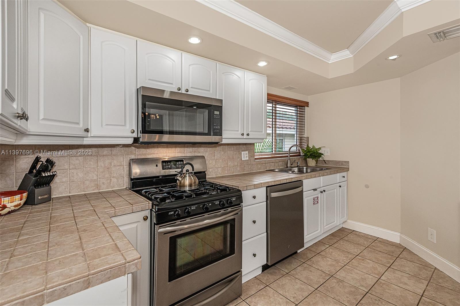 307 North Rainbow Drive Hollywood, FL 33021 - Photo 48 of 74 a kitchen with granite countertop white cabinets and stainless steel appliances