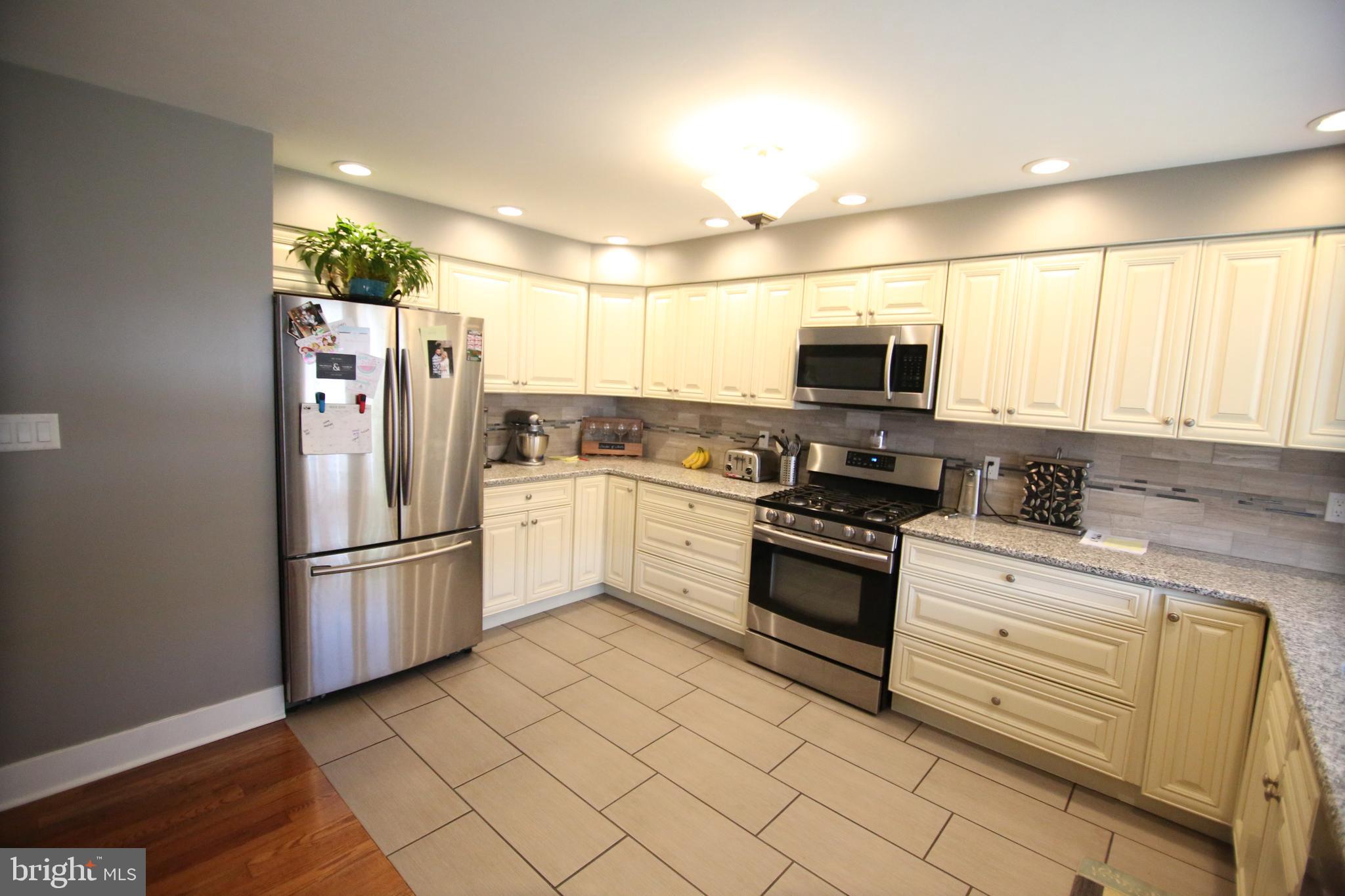 12604 Medford Road Philadelphia, PA 19154 - Photo 4 of 28 a kitchen with granite countertop a refrigerator and a stove top oven