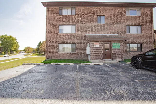 a view of a brick house with a yard and a car parked