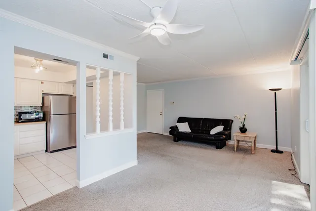 a living room with furniture and a refrigerator