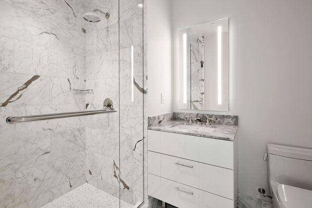 a bathroom with a granite countertop sink a mirror and shower