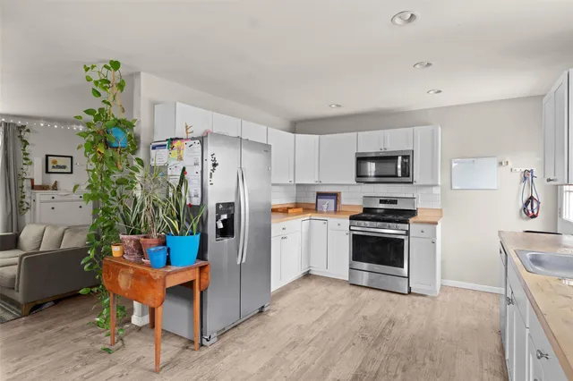 a kitchen with stainless steel appliances a stove a refrigerator a sink a stove a dining table and chairs