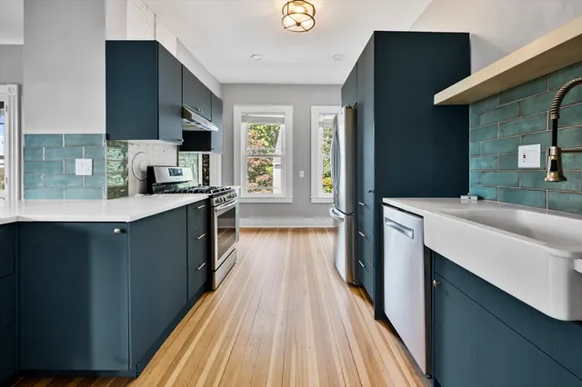 a kitchen with stainless steel appliances a sink dishwasher stove refrigerator and wooden floor
