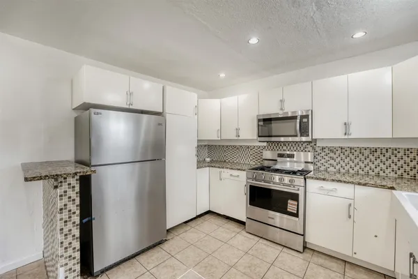a kitchen with white cabinets and stainless steel appliances