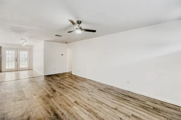 a view of empty room with wooden floor and fan