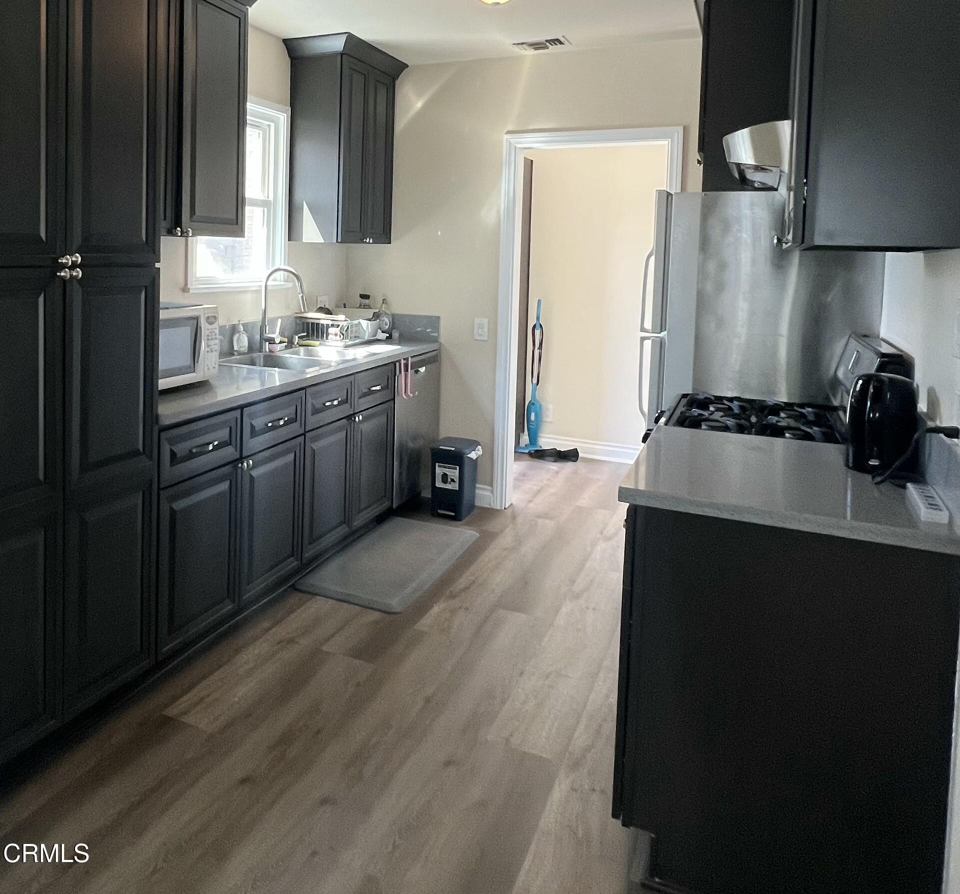 7618 Summitrose Street Tujunga, CA 91042 - Photo 10 of 15 a kitchen with stainless steel appliances a sink dishwasher a refrigerator and a stove with wooden floor